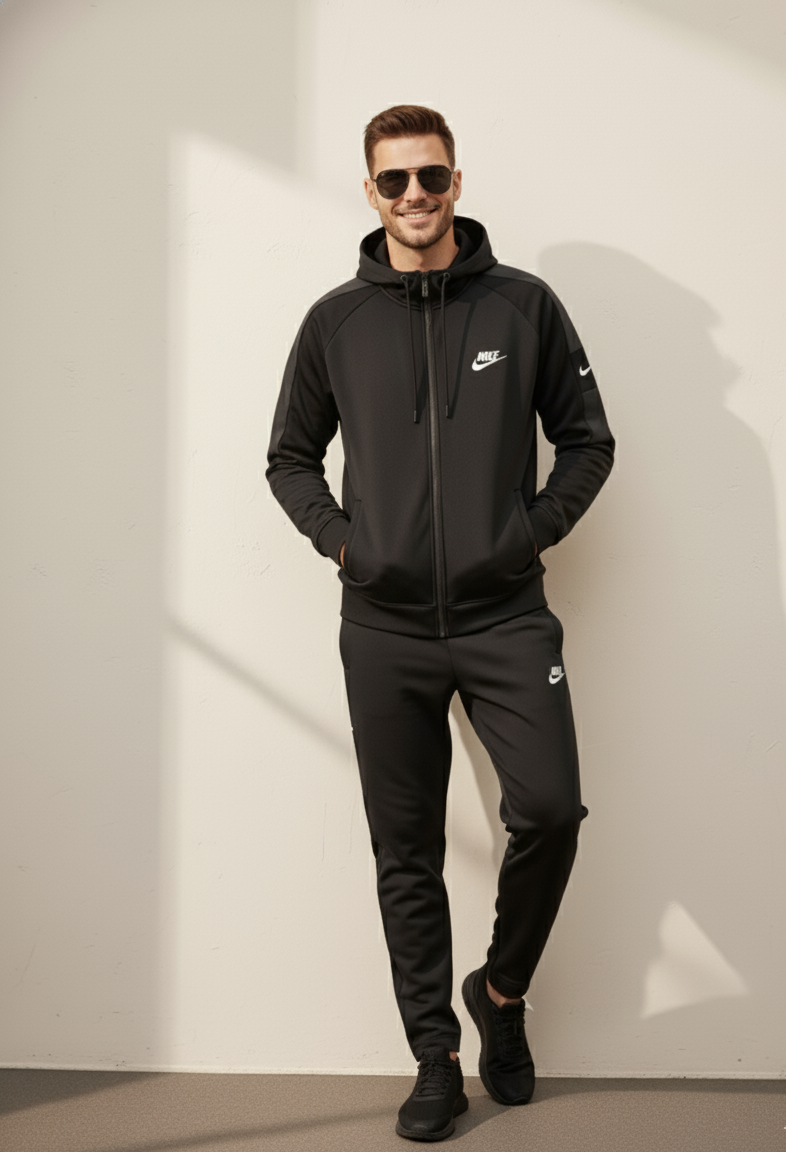 Nike Interlock Polyester Fleece Tracksuit Black worn by model standing against wall